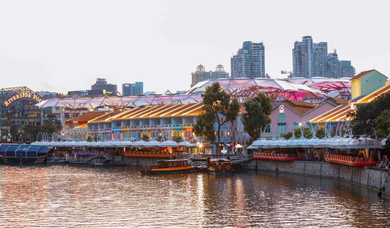 Una escena nocturna con barcos que pasan por Clarke Quay en Singapur