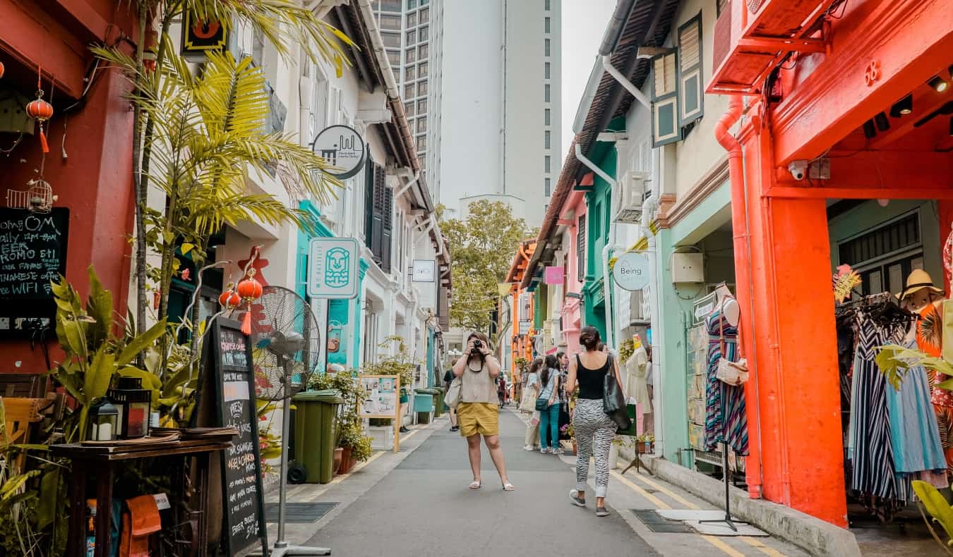 Gente tomando fotos y caminando por Haji Lane, un callejón peatonal lleno de tiendas y puestos de colores en el barrio de Kampong Glam, Singapur