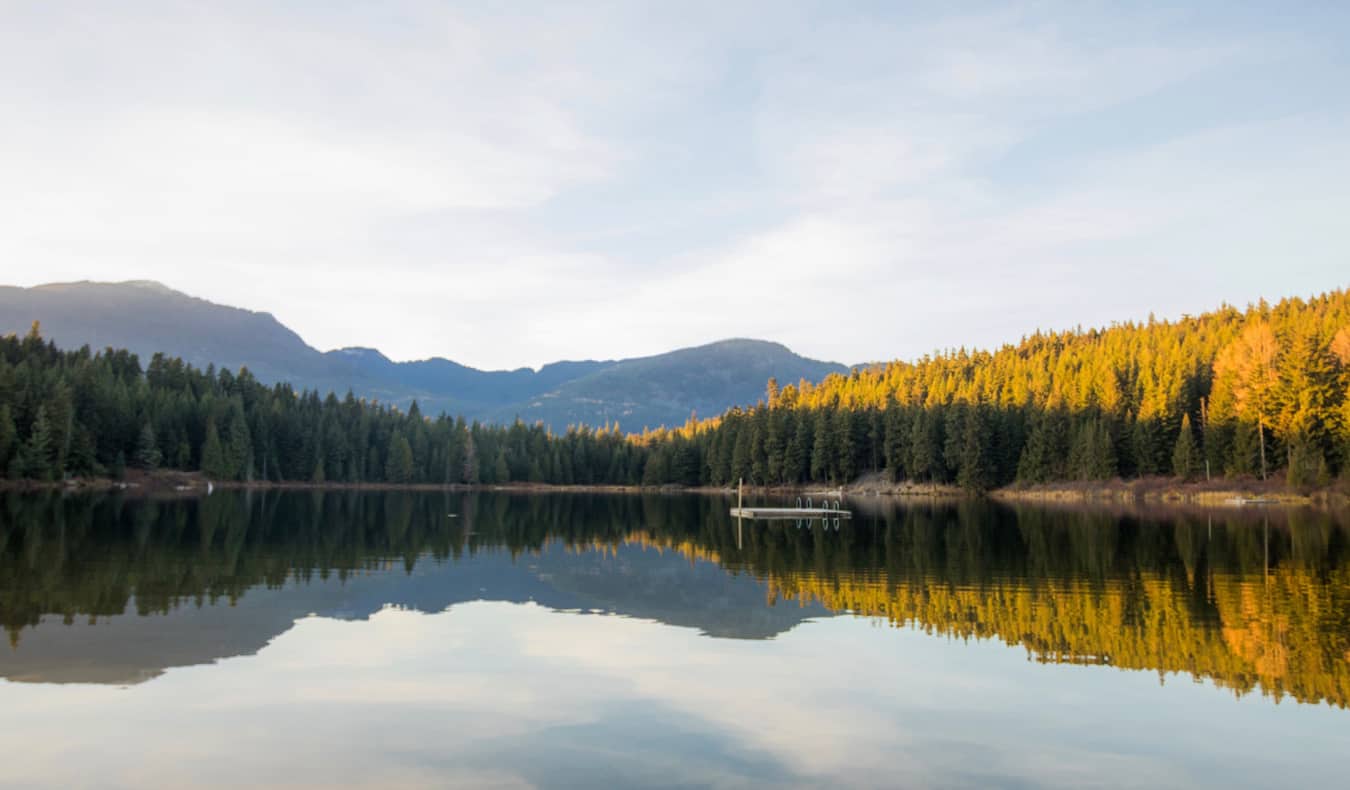 Un lago tranquilo con un pequeño muelle flotante cerca de Whistler, BC, Canadá