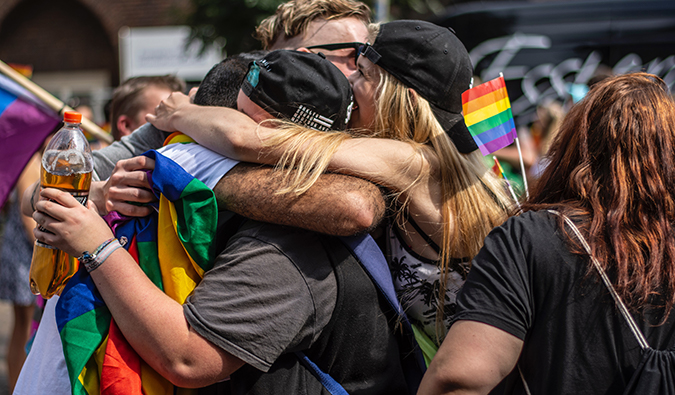 mujeres abrazadas en medio de un desfile del orgullo