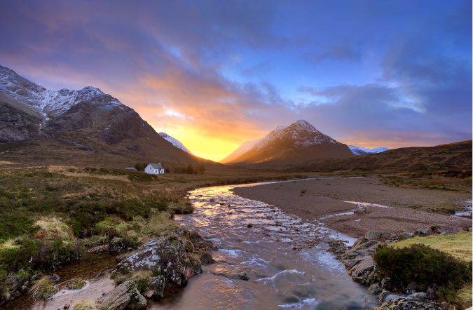 Fotografía de un río y montaña y una puesta de sol colorida