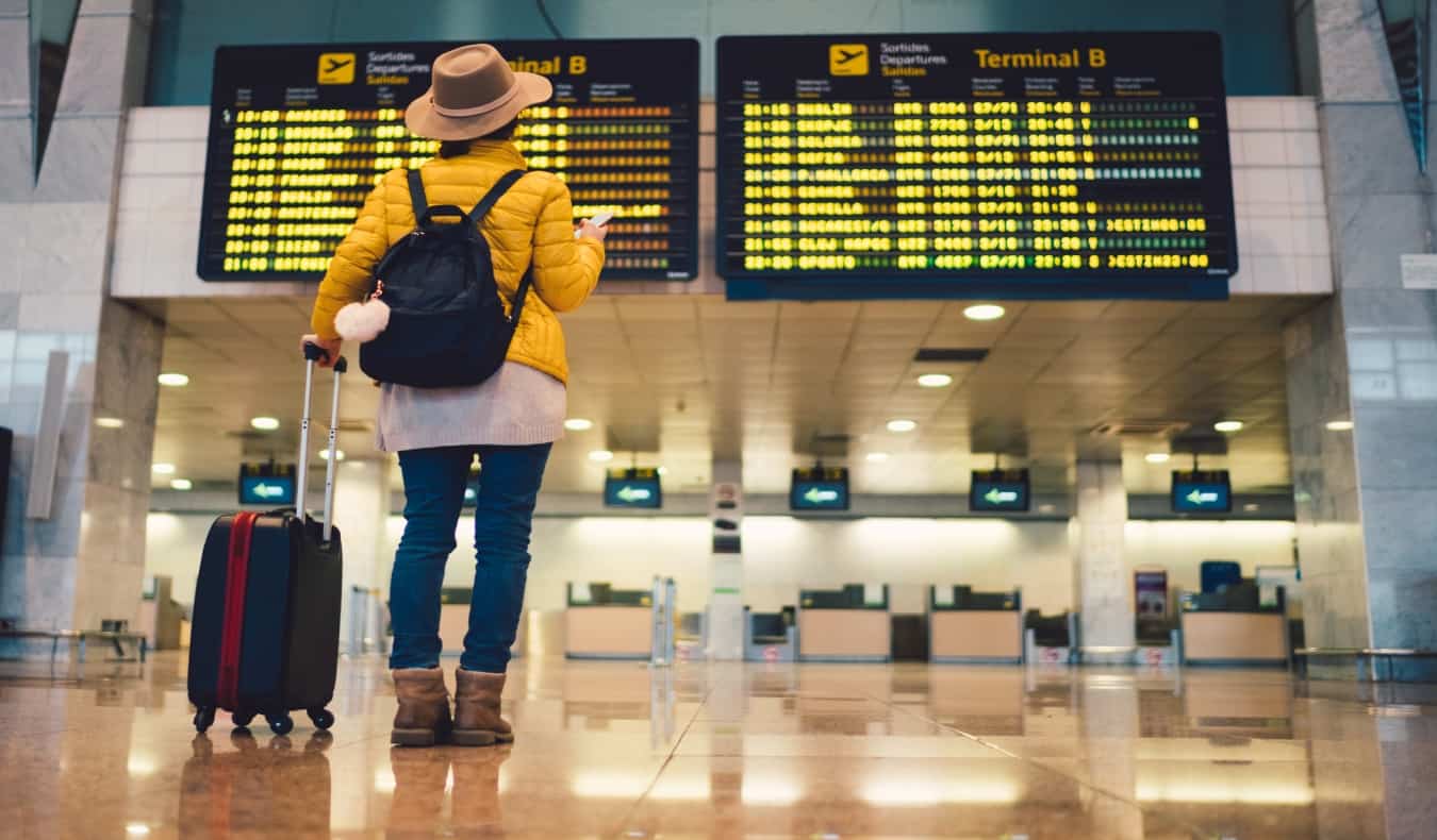 mujer parada frente al tablero de salidas en el aeropuerto de Barcelona