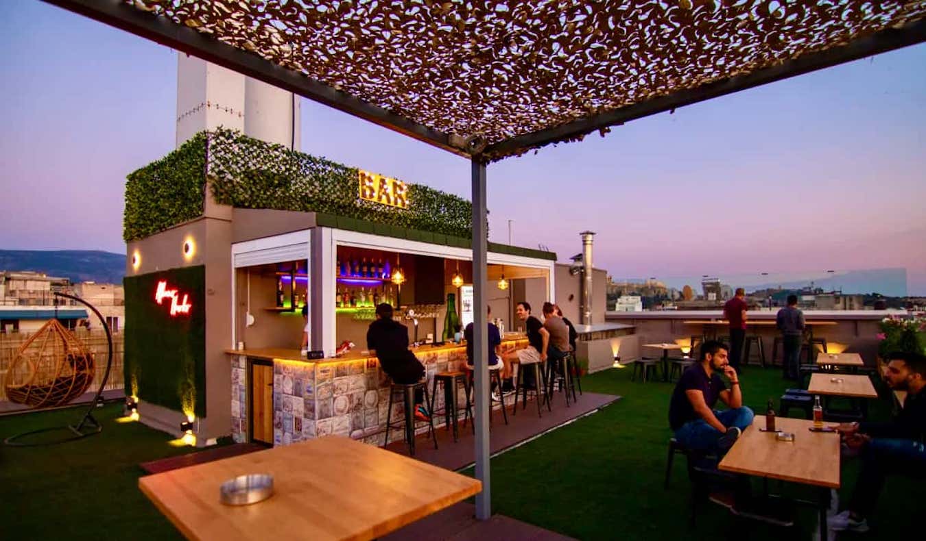 La gente pasa el rato en un bar en la azotea del Athens Hawks Hostel en Grecia durante la puesta de sol