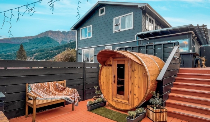 Sauna esférica en una cubierta con una gran casa al fondo en el albergue Black Sheep Backpackers en Queenstown, Nueva Zelanda