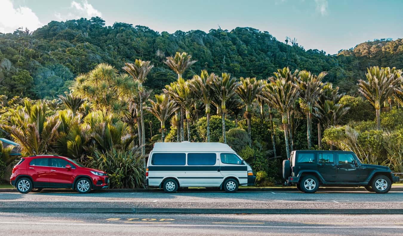 Un coche, una autocaravana y un jeep en la carretera en las selvas tropicales de Nueva Zelanda.