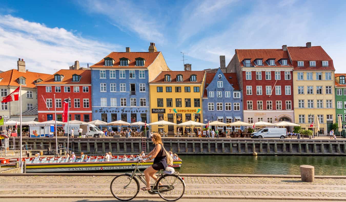 Los edificios de colores de Copenhague a lo largo del agua mientras alguien pasa en bicicleta