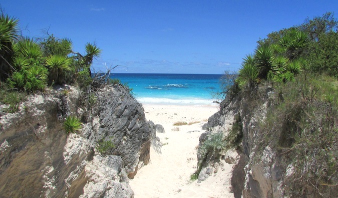 Entrada de arena en la playa del Caribe flanqueada por dos grandes rocas hierbas