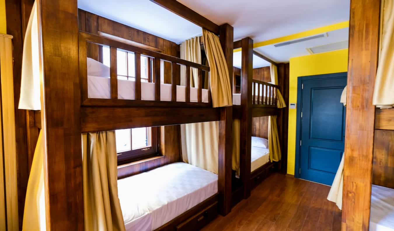 El interior del Yolo Hostel en Estambul, Turquía, con literas de madera y cortinas en un dormitorio pequeño