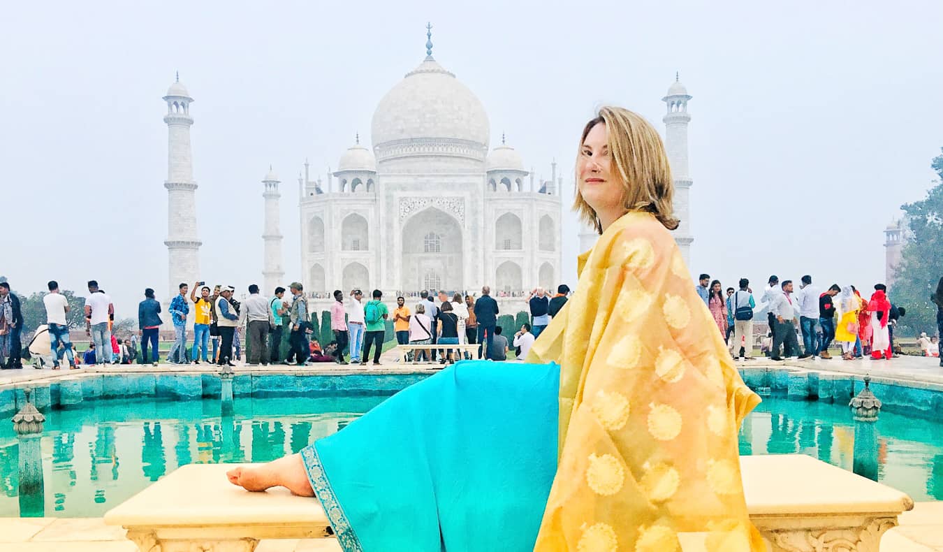 Una viajera en solitario con un sari de colores posando frente al Taj Mahal en la India