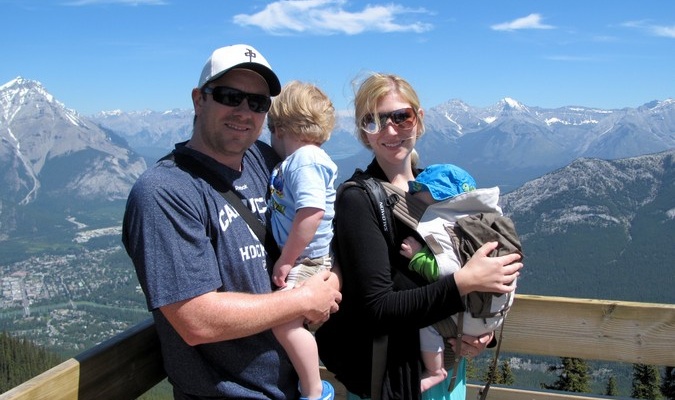 Familia de cuatro personas que viajan frente a una cordillera nevada