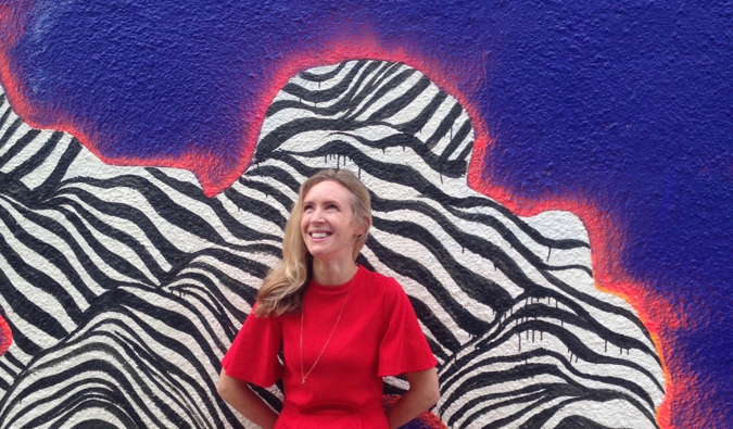 La autora más vendida Helen Russell poniendo frente a un mural de colores