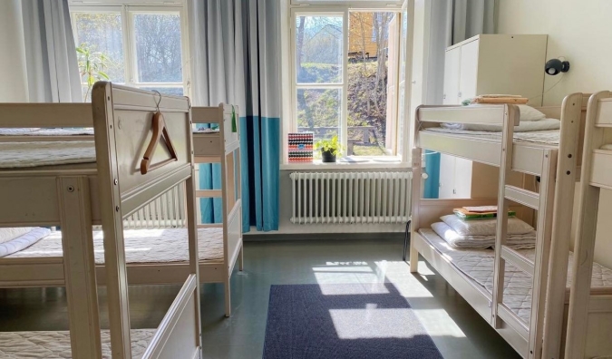 Dormitorio en el Hostel Suomenlinna en Helsinki, Finlandia, con literas de madera blanca y luz natural que entra.