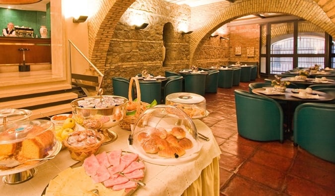 Desayuno buffet en la zona de comedor con techos arqueados de piedra del Hotel Laurentia en Roma, Italia