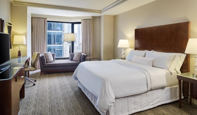 Cama grande blanca nítida en una habitación sencilla pero de diseño moderno con vistas a la ventana del Westin Chicago River North Hotel