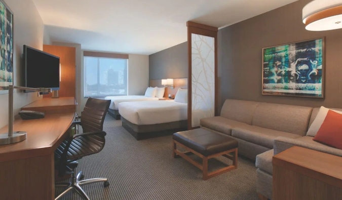 Habitación del Hyatt Place Chicago South con dos camas grandes, un escritorio y un sofá seccional grande