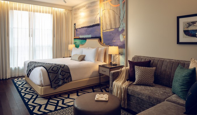 Habitación de lujo con cama extragrande en el hotel Sophy Hyde Park de Chicago, decorada con un estilo contemporáneo con una cama grande y un sofá seccional gris