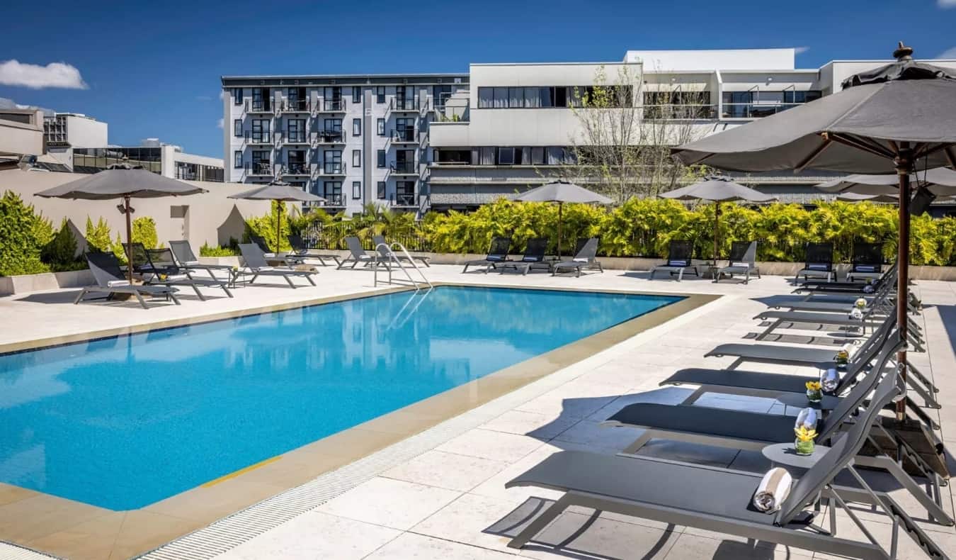 Piscina exterior rodeada de hamacas en el hotel Cordis de Auckland, Nueva Zelanda