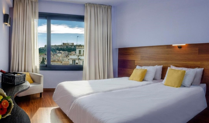 Habitación del hotel Athens Center Square con una ventana abierta que muestra la Acrópolis a lo lejos