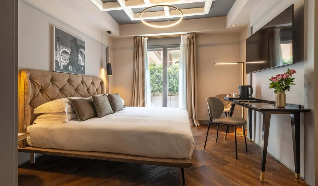 Cama grande, escritorio y TV en la pared en el Loly Boutique Hotel en Roma, Italia