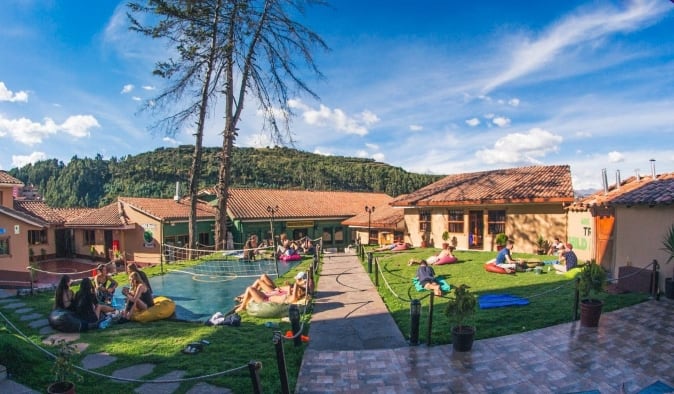 Amplia zona ajardinada con gente jugando a juegos de jardín y relajándose en Wild Rover, un albergue en Cusco, Perú