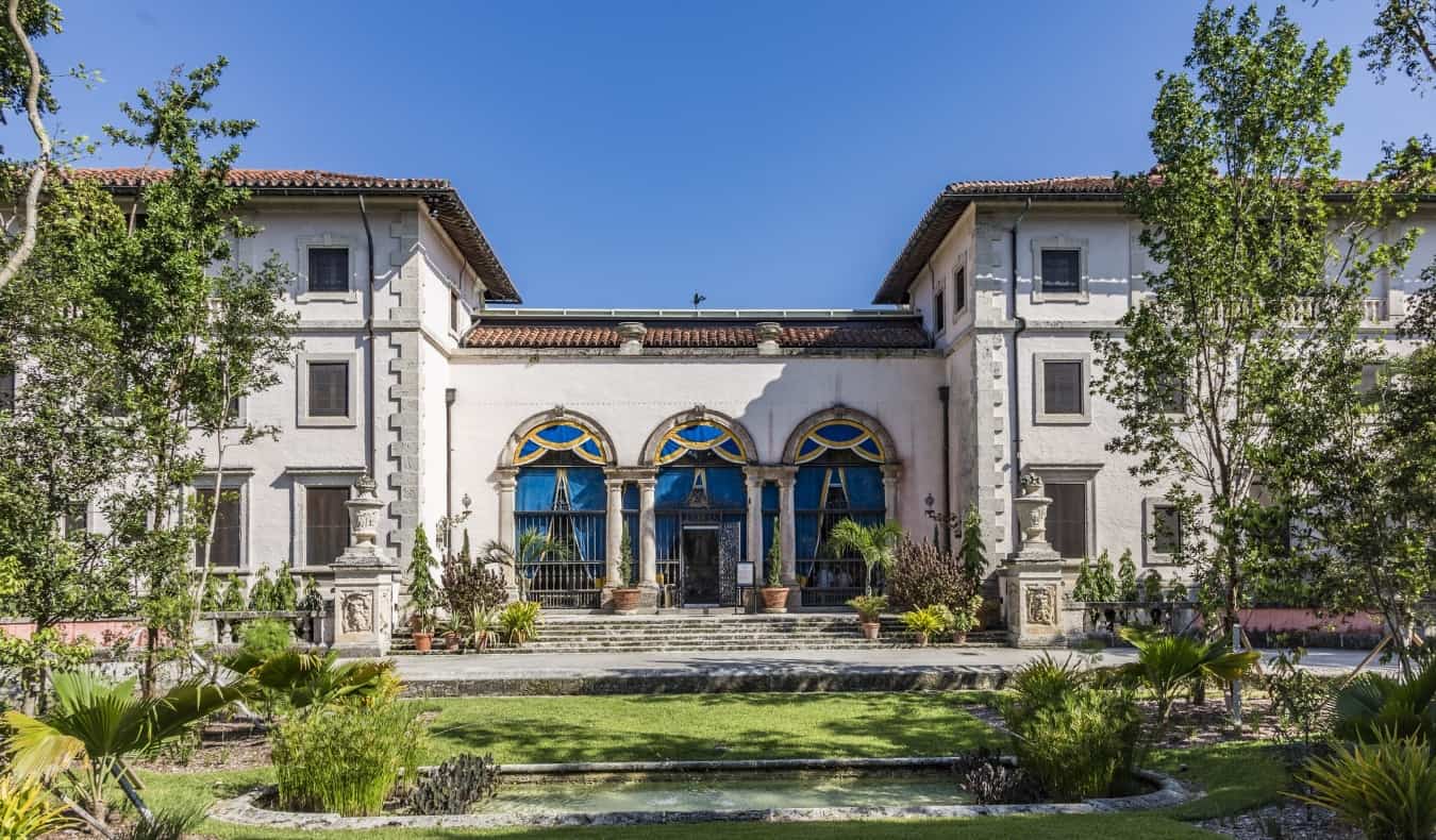 The Vizcaya Estate con un techo de terracota y grandes puertas de arco bajo cielo azul en Miami, Florida.