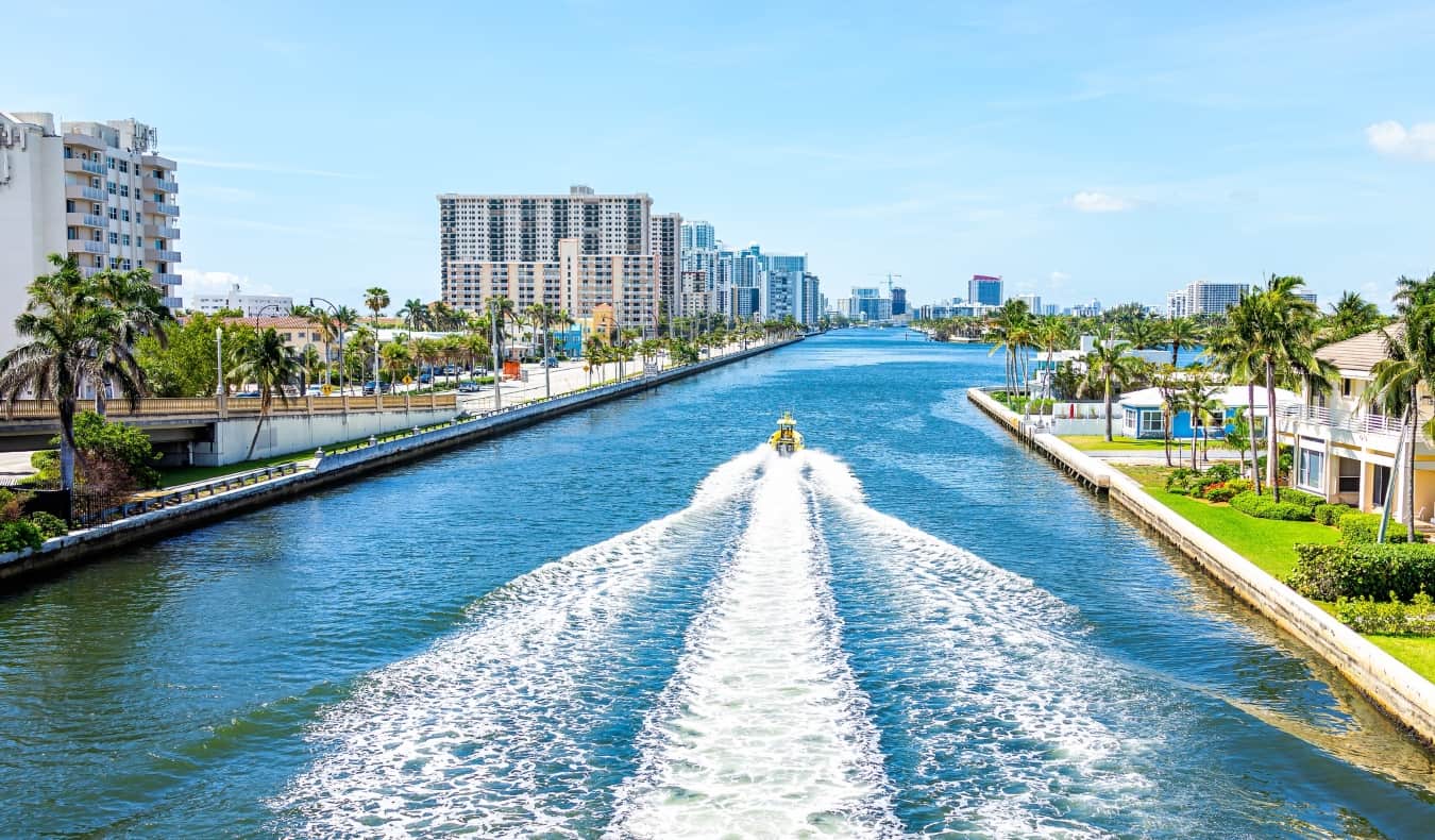 Un barco navega por un gran canal lleno de edificios de apartamentos y palmeras en Miami, Florida