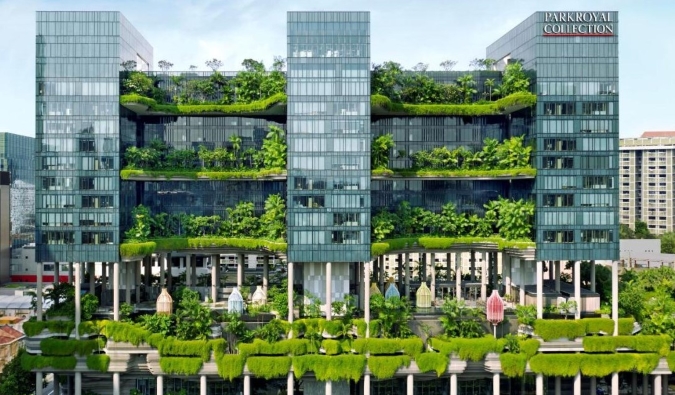 El exterior de PARKROYAL COLLECTION Pickering, un hotel de 5 estrellas de Singapur, cubierto de plantas exuberantes que descienden de los balcones.