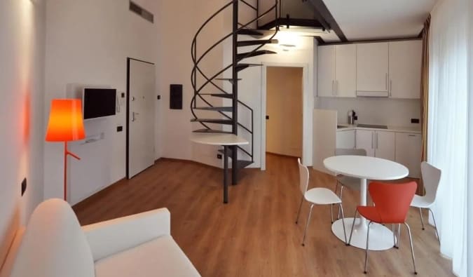 La zona de cocina y sala de estar con una escalera de caracol que conduce a un altillo del BB Hotels Aparthotel Isola en Milán, Italia