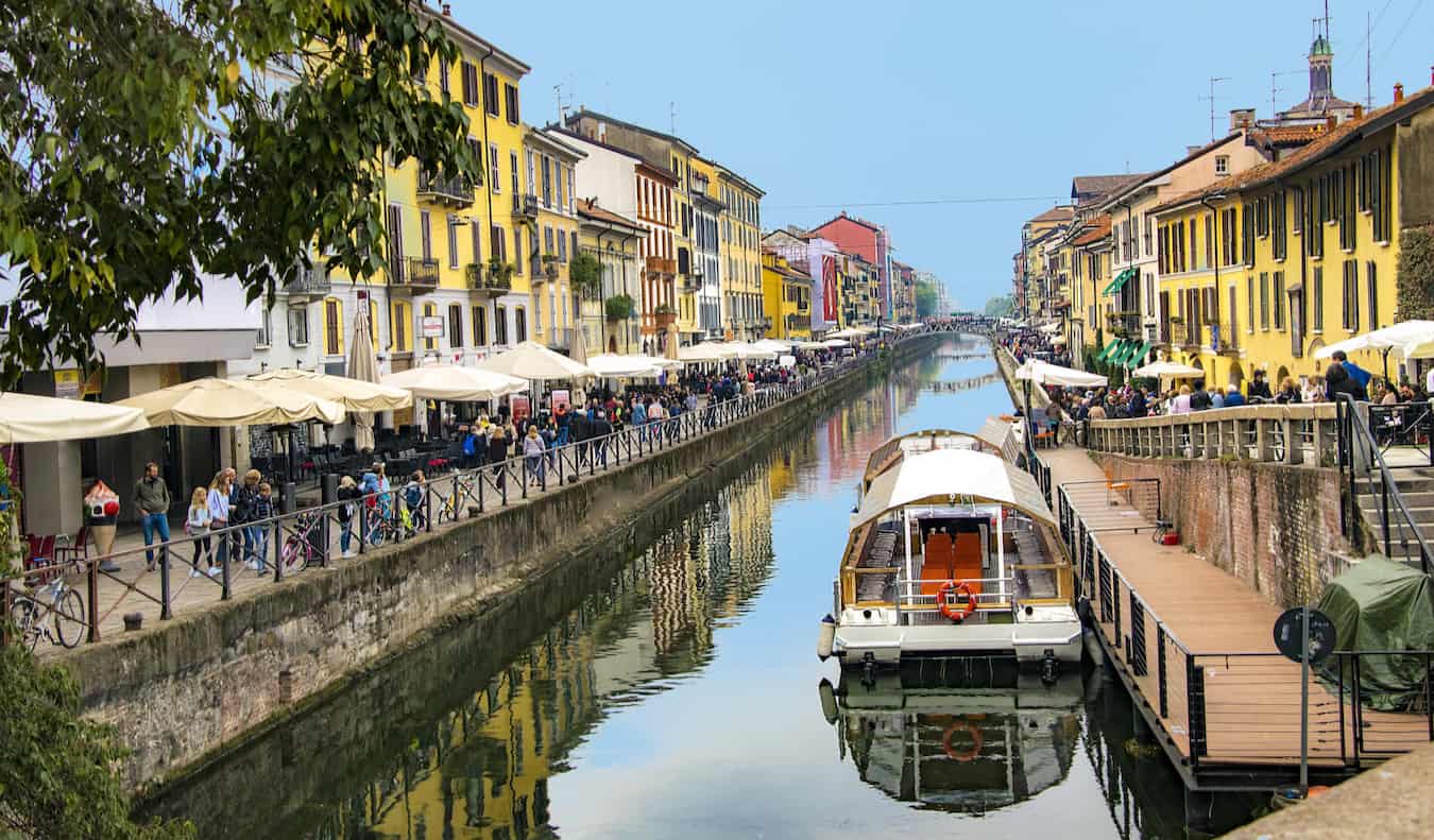 Un canal estrecho rodeado de cafeterías y restaurantes concurridos en la soleada Milán, Italia