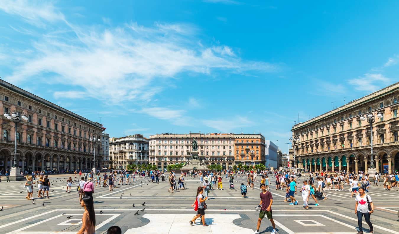 Gente paseando por una enorme plaza abierta en el barrio del Centro Histórico del soleado Milán, Italia