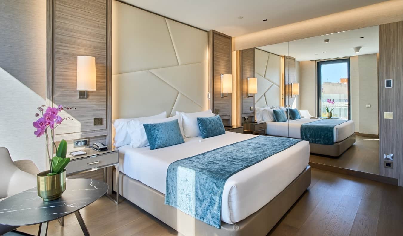 Una cama grande en una habitación de hotel con un diseño contemporáneo, un gran espejo y orquídeas en la mesa de VP Plaza España Design en Madrid, España