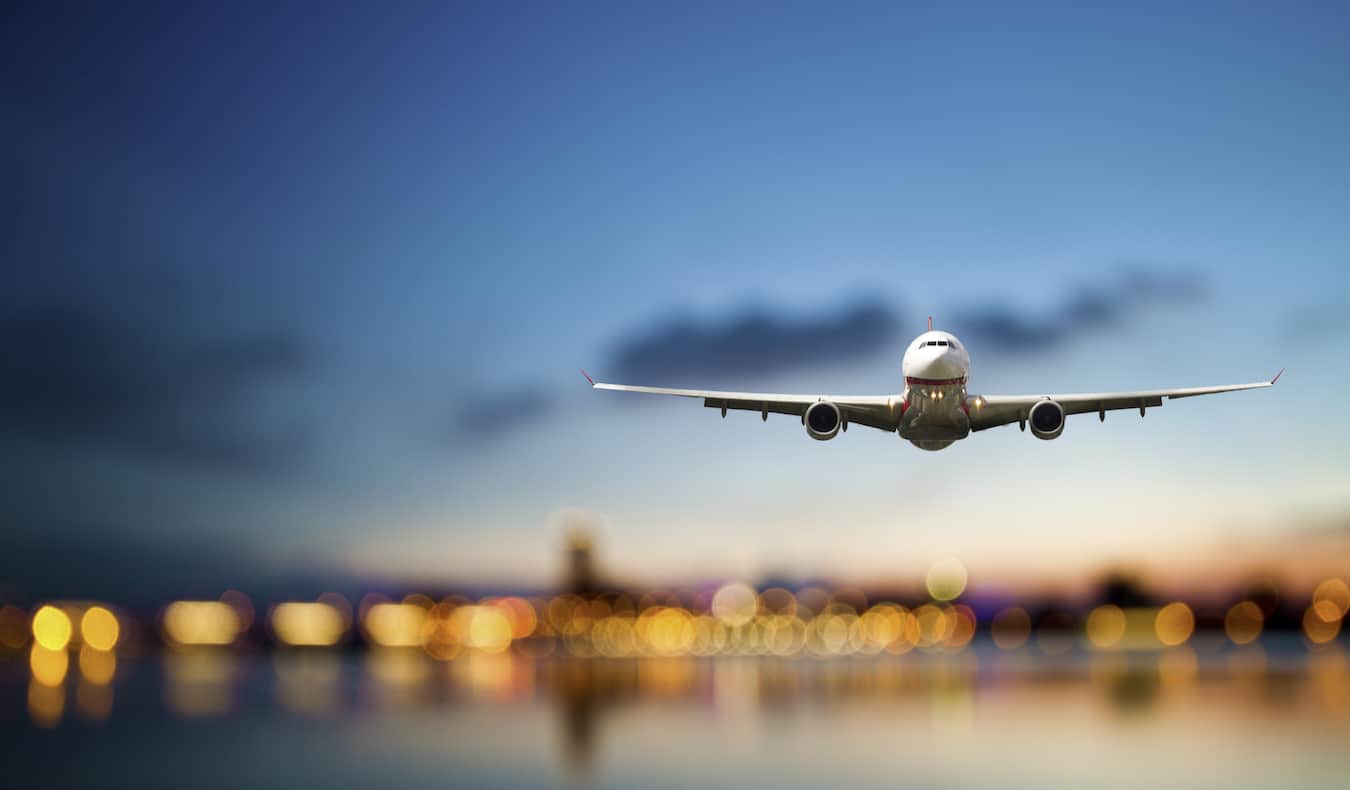 Un enorme avión comercial que vuela por el cielo azul oscuro cuando llega para aterrizar en un aeropuerto