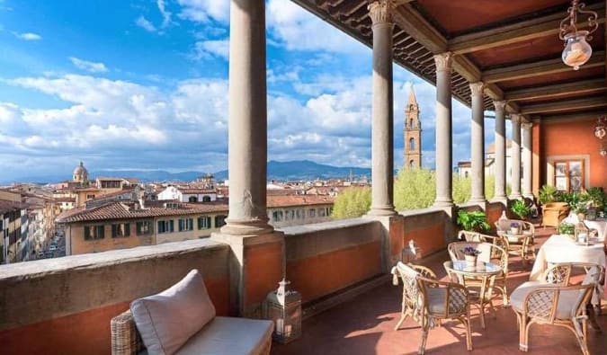 Una terraza en la azotea con sillas y mesas con vistas al paisaje urbano de Florencia, Italia, en el Hotel Palazzo Guadagni