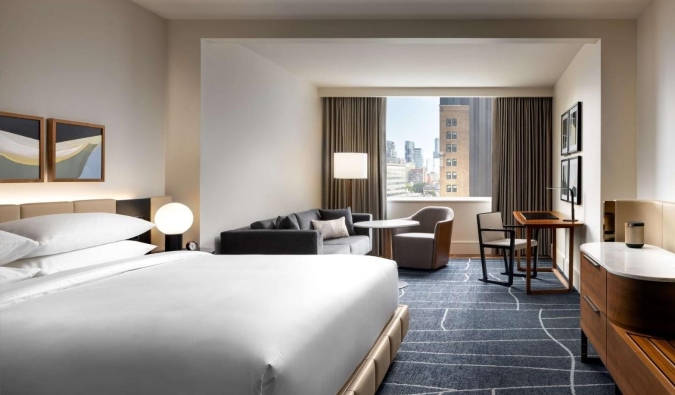 Una habitación grande con una cama grande, sofá, zona de estar, ventanales, todo decorado con un diseño contemporáneo mínimo en el hotel Park Hyatt de Toronto, Canadá