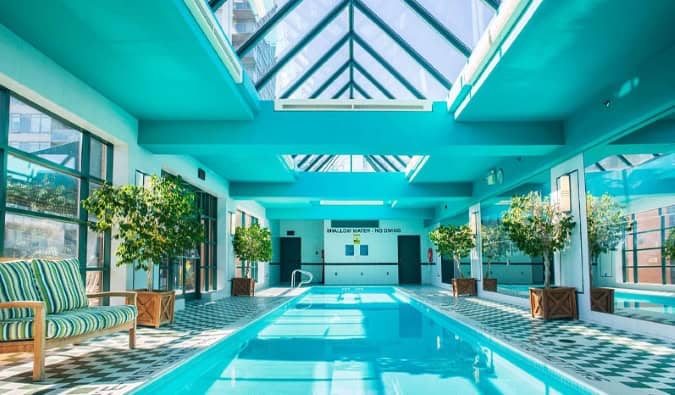 Una larga piscina cubierta forrada de pequeños árboles en maceta en un atrio de cristal en el hotel Yorkville Royal Sonesta en Toronto, Canadá