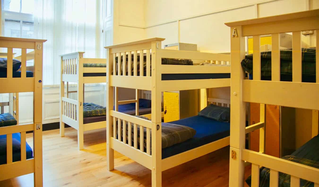 Un dormitorio espacioso y luminoso con muchas literas de madera en Edinburgh Backpackers en Escocia