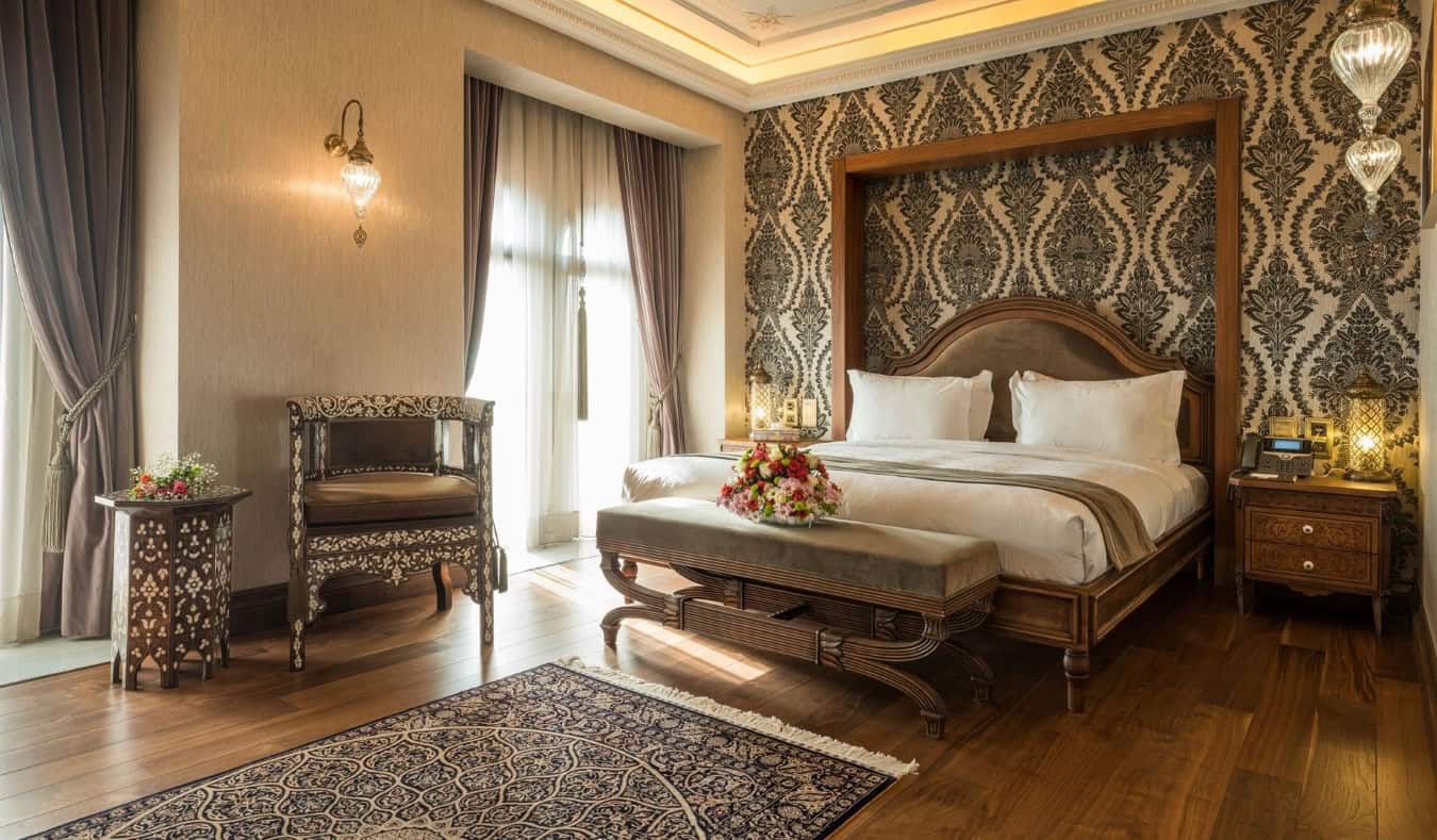 Habitación grande con una cama grande, suelos de madera dura y tapices en las paredes en el AJWA Sultanahmet, un hotel de cinco estrellas en Estambul, Turquía