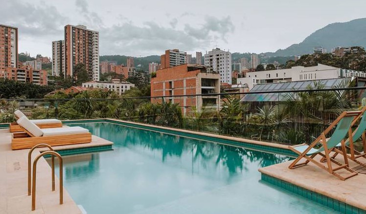 Una piscina en la azotea con vistas a las montañas en el hotel The Click Clack en Medellín, Colombia