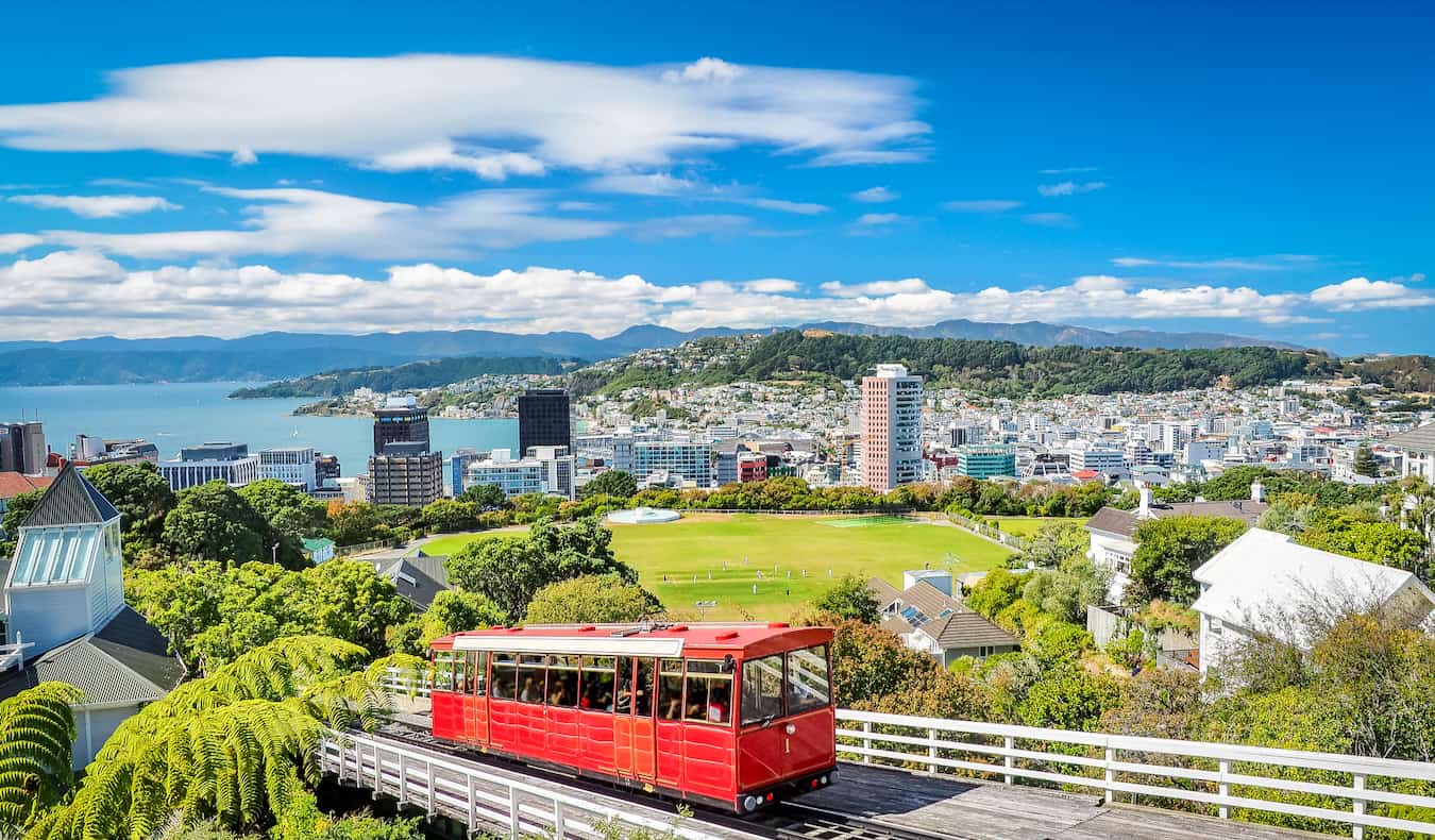 El teleférico rojo subiendo por su pista con el horizonte de Wellington, Nueva Zelanda al fondo